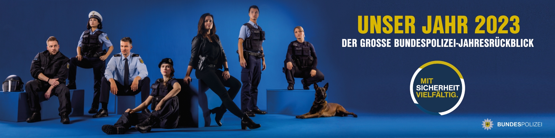 Eine Gruppe von Bundespolizisten in Uniform steht vor mehreren Einsatzfahrzeugen und lächelt in die Kamera. Im Hintergrund sind Flaggen und ein Hubschrauber zu sehen. Auf dem Bild steht: 'Jahresrückblick 2023 – Die Bundespolizei im Einsatz'. Relevante Begriffe: Bundespolizei Jahresrückblick, Bundespolizei Einsätze 2023, Erfolge der Bundespolizei.