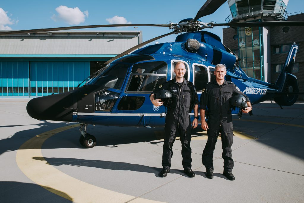 Zwei Bundespolizisten vor ihrem Helikopter mit Helm